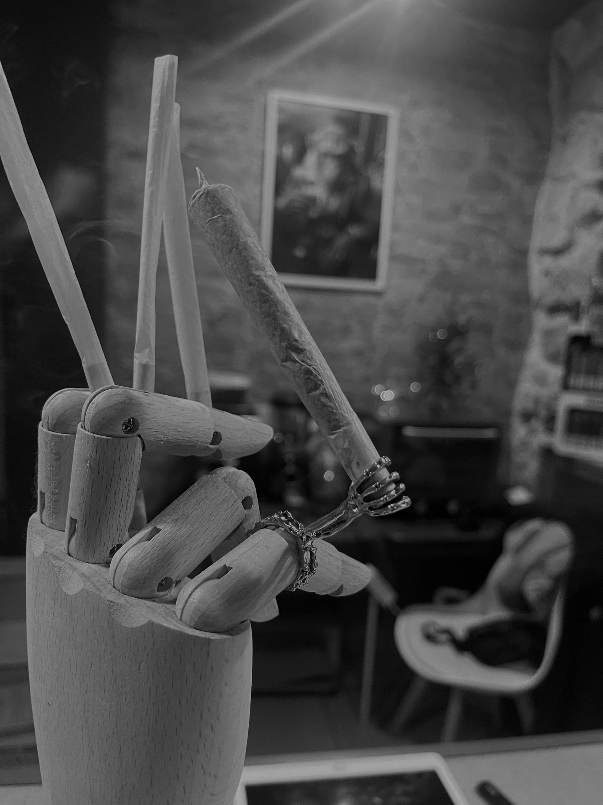 Artist's wooden hand holding a joint in a peace sign